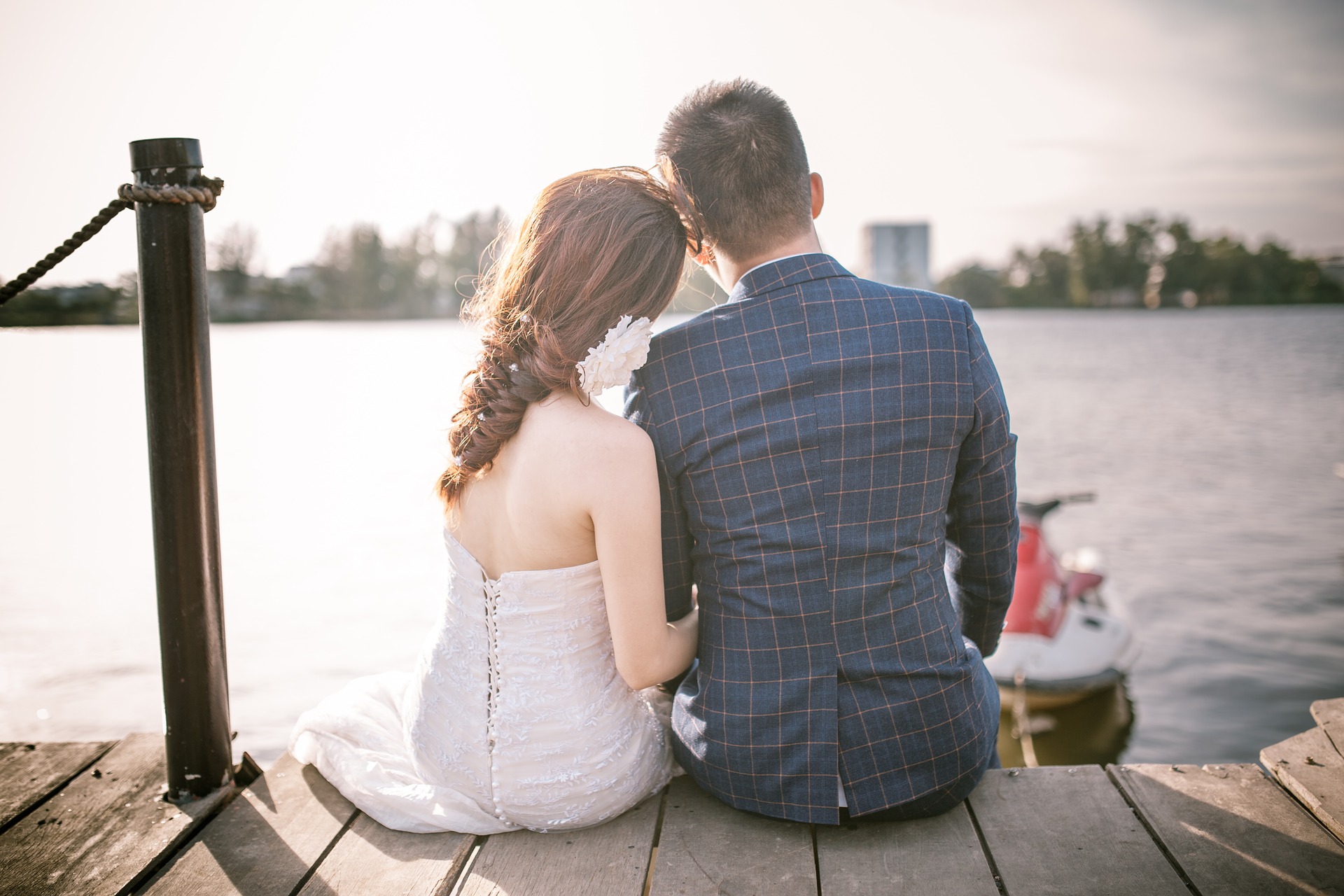 coppia in viaggio di nozze, seduta sul ciglio di un lago mentre ammira l'orizzonte.